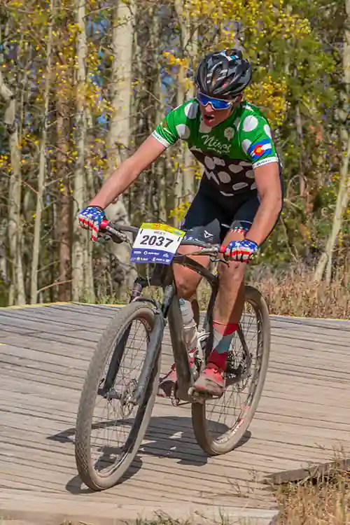 Niwot rider descends off the ramps with fall colors in the background at Granby Ranch